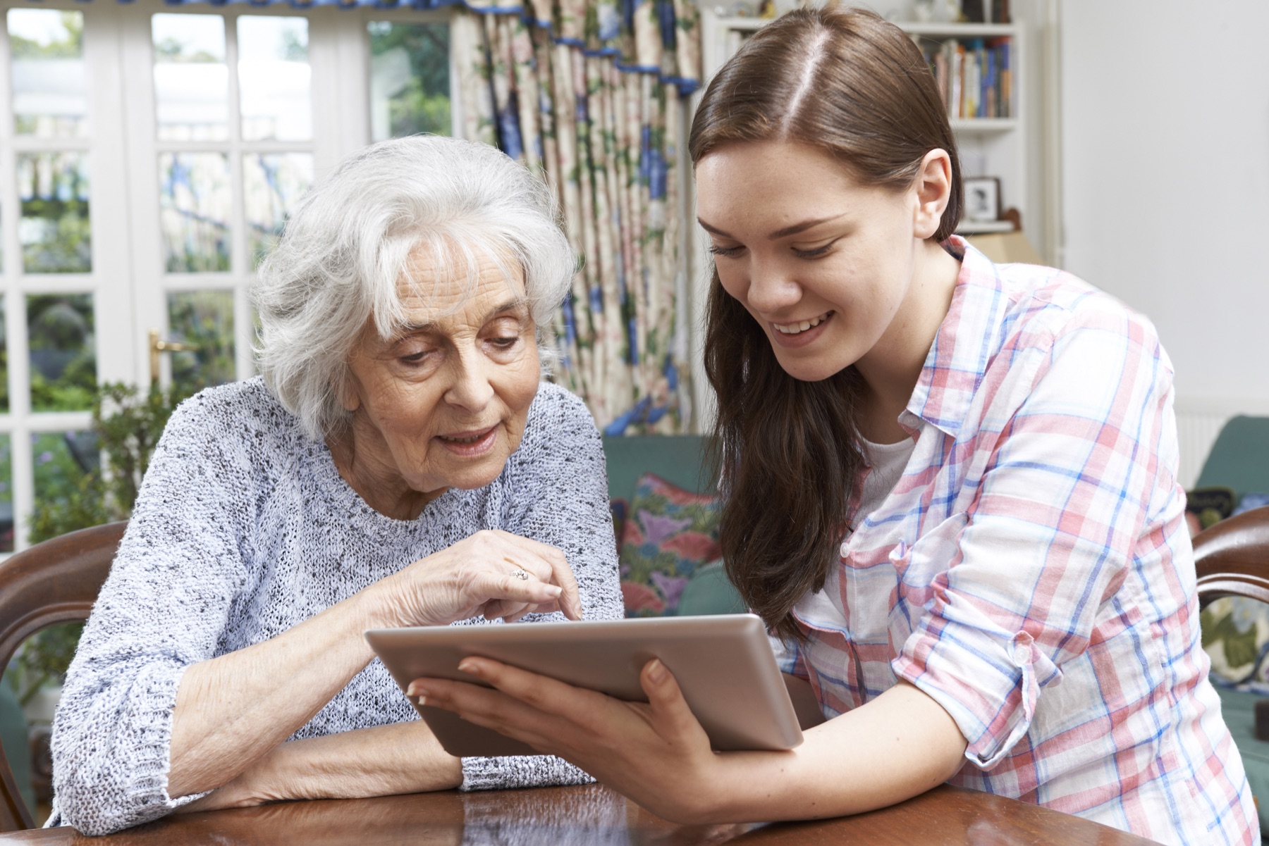A granddaughter showing her grandmother a tablet