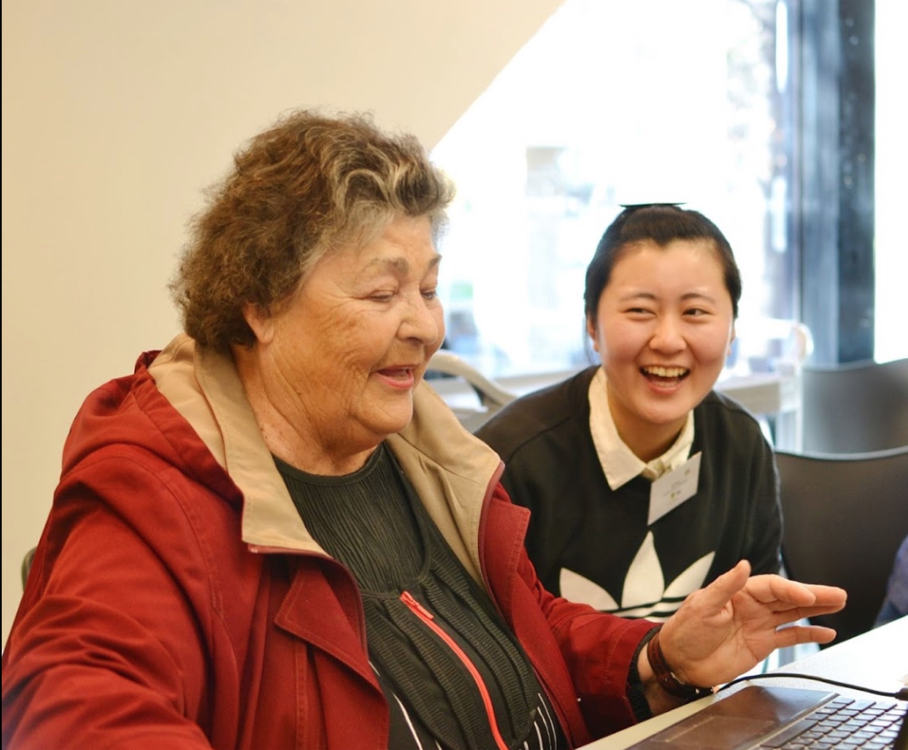 An older woman and a younger woman laughing together at a laptop