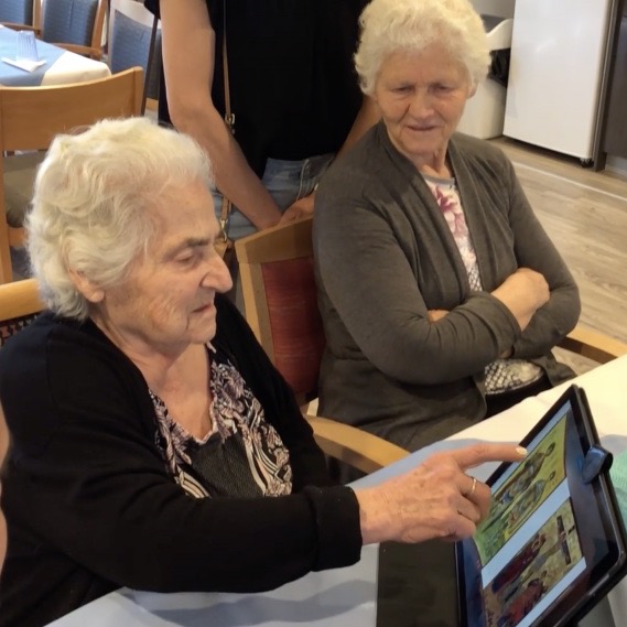 A resident pointing at a tablet during a Mentia session in a care home